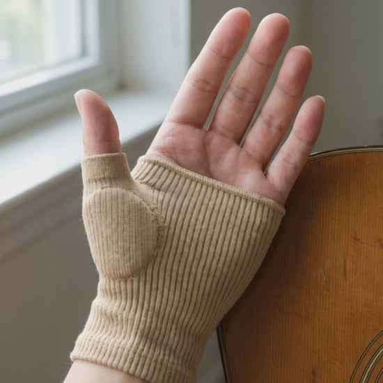A hand wearing the beige knit thumb sleeve resting against an acoustic guitar, five second clip